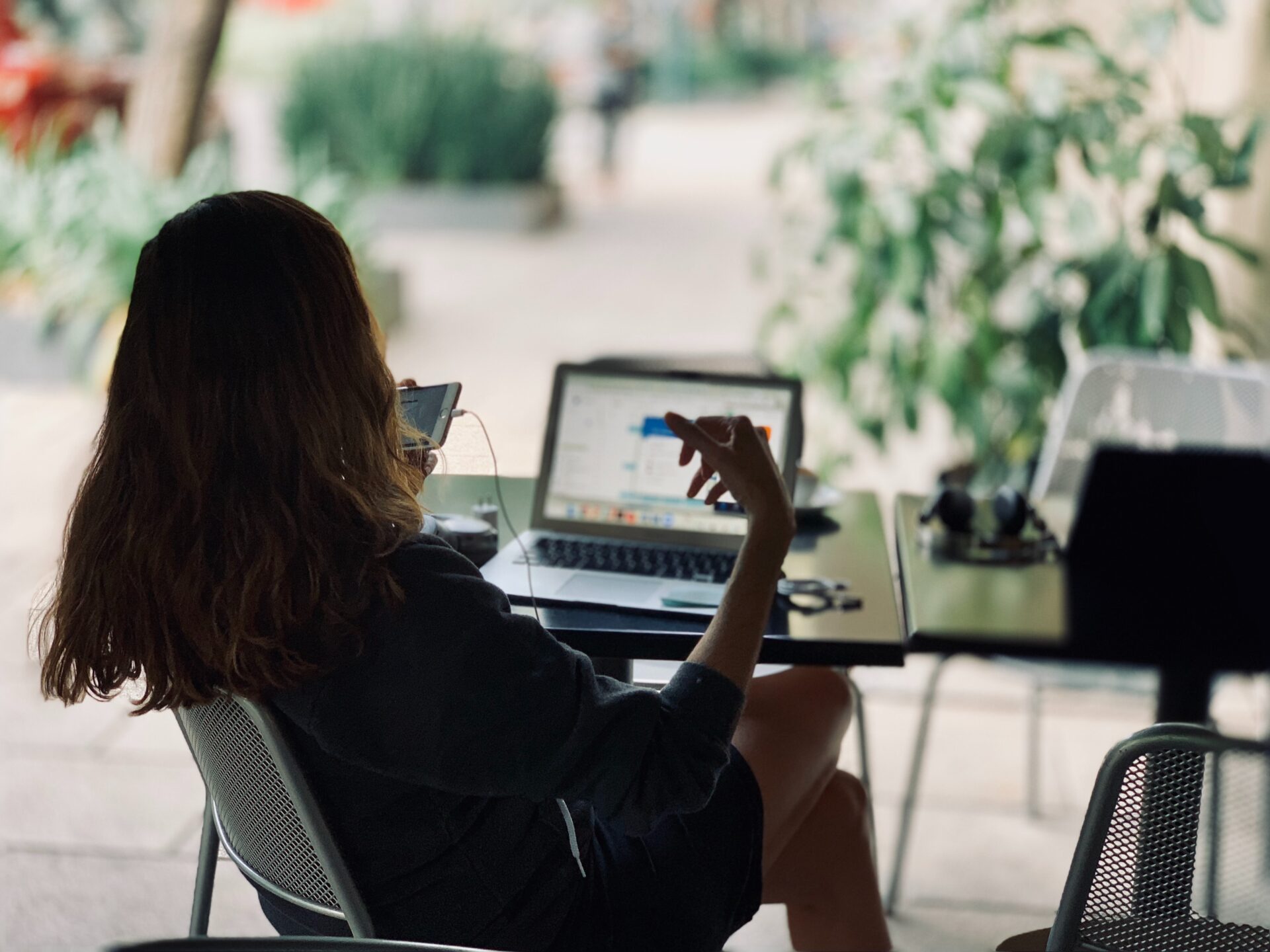 A woman sits in a chair in Mexico on a phone with a laptop open in front of her.