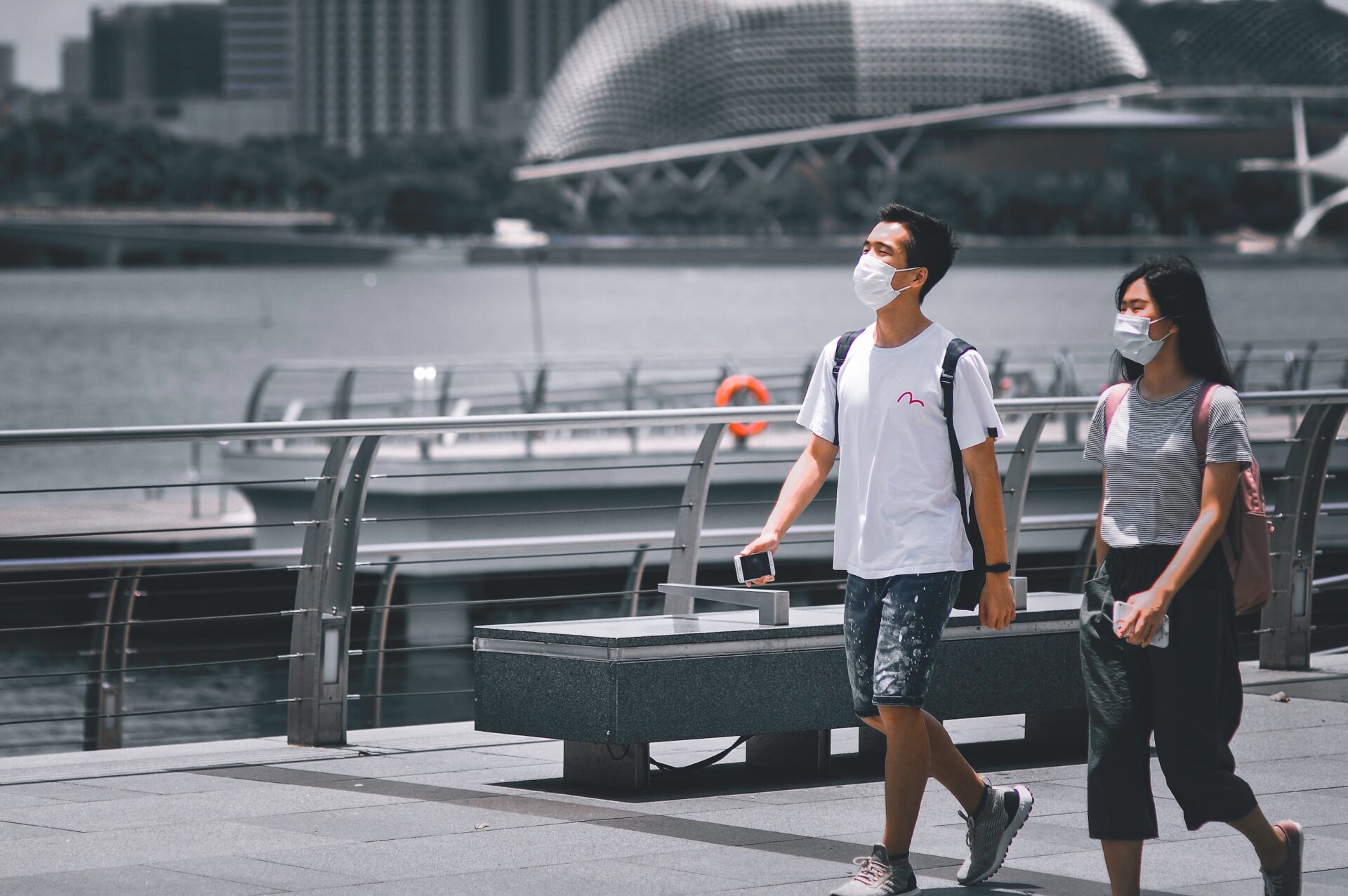 A woman and man, wearing masks, walk down the street at Marina Bay in Singapore.
